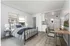 Bright studio apartment with a comfortable bed, modern kitchenette, and a sleek work desk.