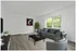 Bright and airy living room with modern decor, featuring a comfortable gray sofa, a sleek coffee table, and large windows with green views.