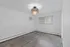 Bright empty room with sleek hardwood flooring, modern chandelier, and air conditioning unit under sunlight from a large window.