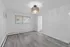 Modern bright room with elegant chandelier, sleek flooring, and large window for natural light.