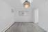 Bright and airy room with elegant chandelier, modern flooring, and large window for natural light.
