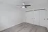 Modern bedroom with sleek ceiling fan and spacious double closet doors, featuring stylish wood flooring.