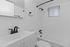 Bright modern bathroom with sleek black fixtures, white tile walls, and a convenient shower-tub combo.