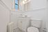 Bright, modern bathroom with classic white vanity, elegant fixtures, and stylish black and white tile flooring.