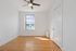 Bright room with polished hardwood floors, a large window, and a sleek ceiling fan, perfect for a cozy bedroom.