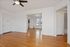 Bright living space with elegant hardwood flooring, modern ceiling fan, and ample natural light through large windows.