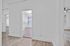 Charming hallway featuring modern light-colored wood flooring and fresh white walls, leading to bright and inviting rooms.