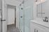 Modern bathroom with elegant glass shower, stylish white subway tiles, and chic patterned flooring.