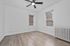 Bright and airy empty room featuring sleek modern ceiling fan, large windows with blinds, and elegant wood flooring.