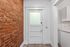 Charming interior entryway with exposed brick wall and classic white door, offering a blend of modern and rustic elegance.