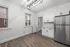 Bright and modern kitchen with sleek stainless steel appliances, elegant white cabinetry, and stylish wood flooring.