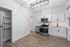 Modern kitchen with sleek white cabinetry, stainless steel appliances, and elegant wood flooring, creating a bright and welcoming space.