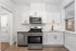 Bright modern kitchen with sleek stainless steel appliances, white cabinetry, and large window offering natural light.