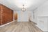 Charming living space with a modern rustic feel, featuring exposed brick walls, elegant light fixture, and sleek wooden floors.