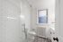 Bright and elegant bathroom featuring modern glass shower, classic white subway tiles, and decorative patterned floor tiles.