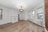 Charming living room with elegant hardwood floors, a classic white fireplace, and large windows offering abundant natural light.