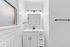 Bright and modern bathroom featuring sleek white cabinetry, elegant lighting, and a contemporary design.