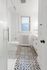 Charming bathroom with elegant patterned tile flooring, sleek glass shower, and classic radiator under a bright window.