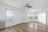 Bright, spacious room with elegant hardwood floors, large windows, and a modern ceiling fan.