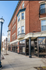 Charming red brick apartment building with large windows and historic architectural details on a sunny street corner.