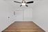 Modern room with sleek ceiling fan, elegant hardwood flooring, and pristine white walls, perfect for a peaceful retreat.