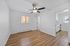 Bright, spacious room with modern ceiling fan, sleek wooden flooring, and access to a cozy kitchen in a stylish apartment.
