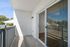 Bright and airy balcony with sleek railing and sliding glass doors, perfect for relaxing outdoors.