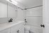 Modern bathroom featuring sleek white cabinetry, a spacious bathtub, and elegant black fixtures.