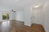 Bright, airy living space with elegant wood flooring, ceiling fan, and sliding glass doors leading to a balcony with lush views.