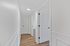 Bright and inviting hallway with elegant white paneling and warm wooden flooring, featuring multiple doors leading to spacious rooms.
