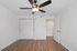 Bright and modern bedroom with elegant ceiling fan and sleek wooden flooring, featuring double closet doors for ample storage.