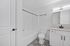Modern bathroom with elegant monochrome tile flooring, a sleek white bathtub, and a stylish vanity with ample lighting.