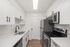 Modern white kitchen with sleek cabinetry, stainless steel appliances, and hardwood flooring.