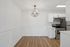 Modern kitchen with sleek stainless steel appliances, elegant chandelier, and polished wood flooring.
