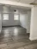 Bright and airy room with stylish hardwood flooring, neutral walls, and abundant natural light from two windows.