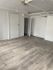 Modern apartment interior with sleek wooden flooring, neutral walls, and an open doorway leading to a closet space.