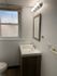 Bright and modern bathroom with a sleek vanity, large mirror, and natural light through a frosted window.