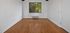 Bright room with hardwood floors, large window, and fresh white walls offering a serene view of greenery.