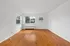 Bright living room with large window, polished hardwood floors, and modern wall unit air conditioner.