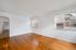 Bright and spacious living area with hardwood floors and large windows overlooking charming neighborhood architecture.