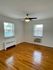 Bright and airy room with hardwood floors, a ceiling fan, and large windows offering plenty of natural light.
