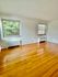Bright room with large windows and polished hardwood floors, offering a serene view of nature.
