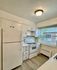 Bright and charming kitchen with white cabinetry, modern appliances, and large window offering natural light.