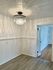 Elegant room with a stunning crystal chandelier casting beautiful light patterns on the ceiling. Features modern flooring and sleek white walls, offering a sophisticated touch to any home.