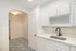 Bright kitchen with elegant monochrome tile flooring, sleek white cabinetry, and modern black faucet.
