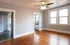 Inviting living space with warm hardwood floors, abundant natural light from large windows, and a stylish ceiling fan for modern comfort.