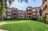 Charming red brick apartment complex with lush green lawn and classic architectural details, perfect for serene living.