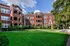 Charming red-brick apartment complex with lush green courtyard and classic architectural details.