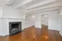 Elegant living room with exposed beams, polished hardwood floors, and a charming fireplace, leading to an inviting dining area with a stylish chandelier.