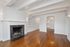 Charming living room with hardwood floors, elegant fireplace, and a glimpse of the kitchen with a sparkling chandelier.